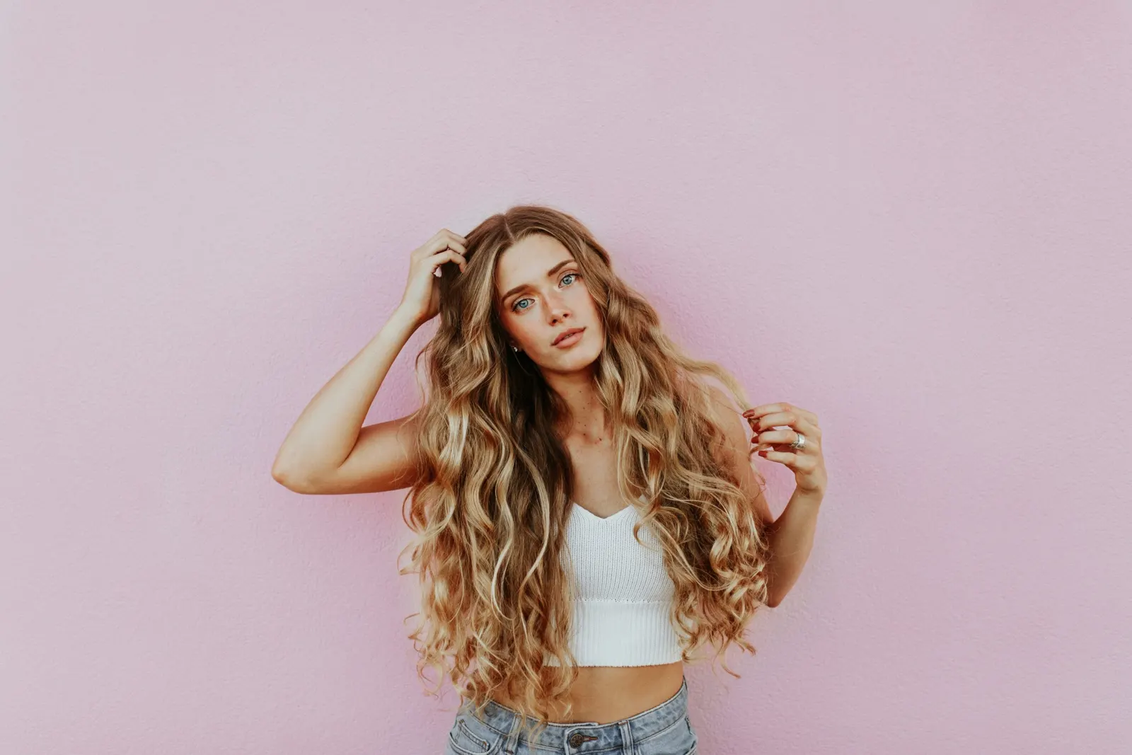 Cliente com cabelo comprido encaracolado sobre fundo rosa