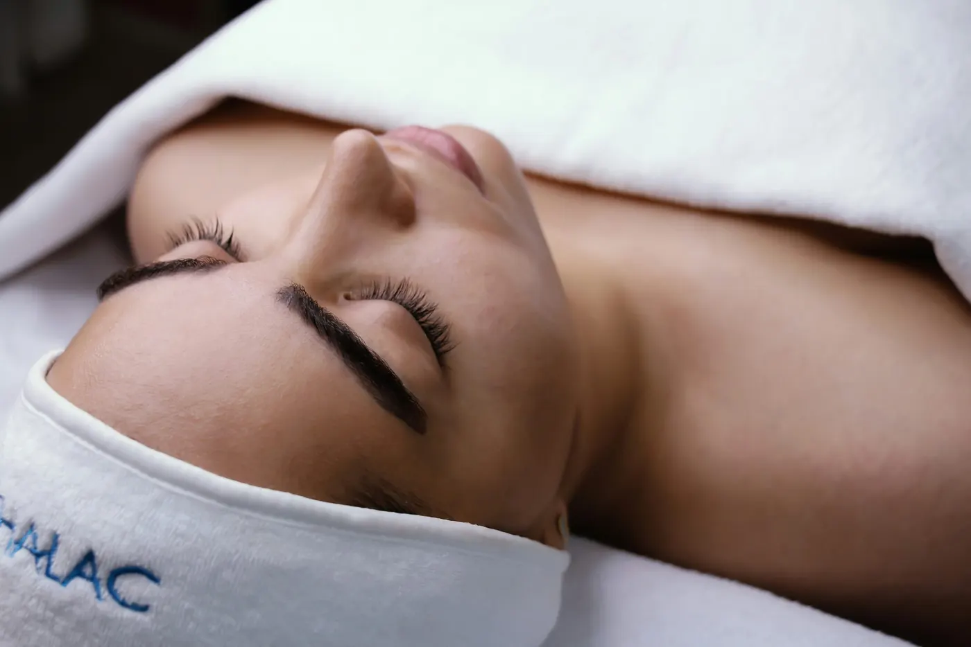 Cliente de olhos fechados durante um tratamento de rosto